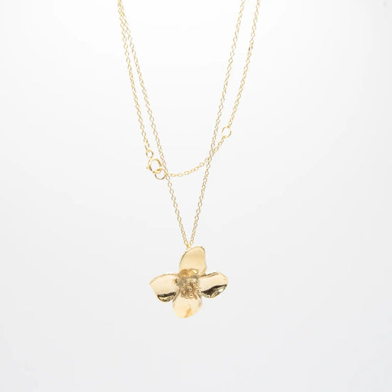 Colgante minimalista con flor de cuatro pétalos en acabado dorado sobre plata de ley 925, cadena fina, joyería artesanal Pipa Pirita colección De la Tierra