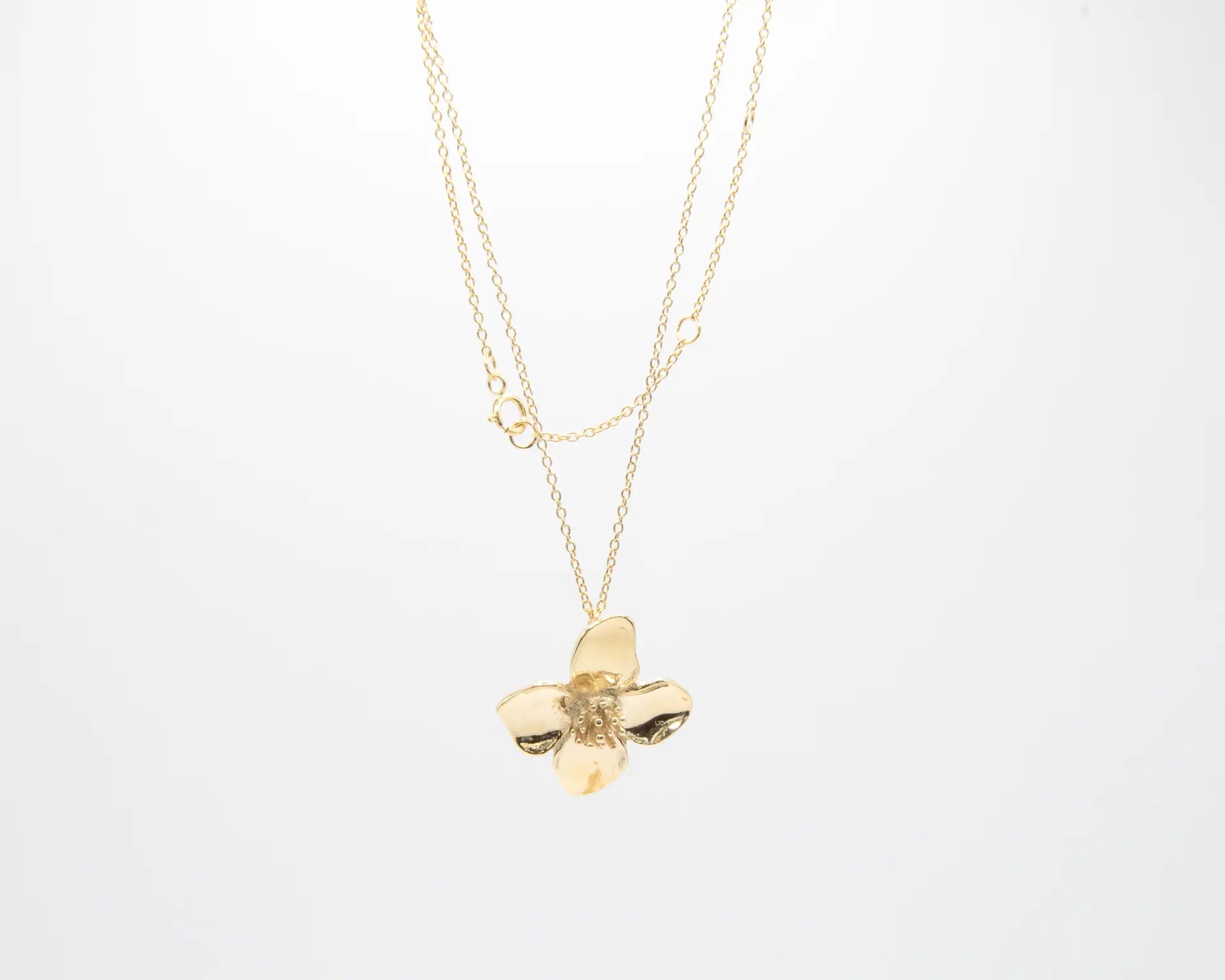 Colgante minimalista con flor de cuatro pétalos en acabado dorado sobre plata de ley 925, cadena fina, joyería artesanal Pipa Pirita colección De la Tierra