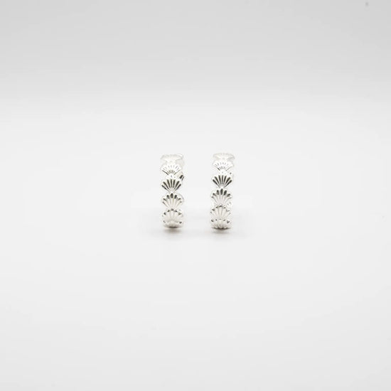 Pendientes de aro en plata de ley con detalle de conchas marinas esculpidas, cierre de presión y acabado artesanal de la marca de joyas Pipa Pirita.