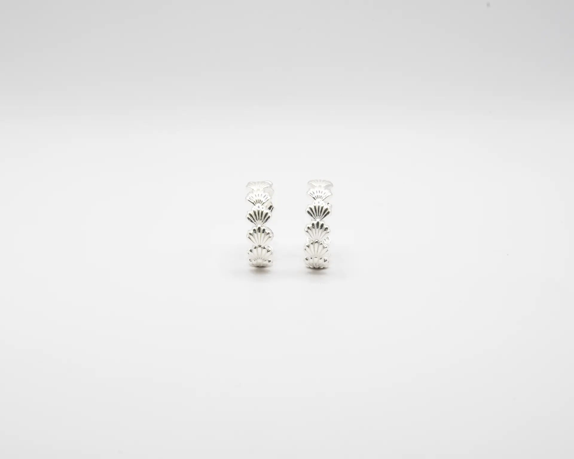 Pendientes de aro en plata de ley con detalle de conchas marinas esculpidas, cierre de presión y acabado artesanal de la marca de joyas Pipa Pirita.