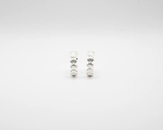 Pendientes de aro en plata de ley con detalle de conchas marinas esculpidas, cierre de presión y acabado artesanal de la marca de joyas Pipa Pirita.