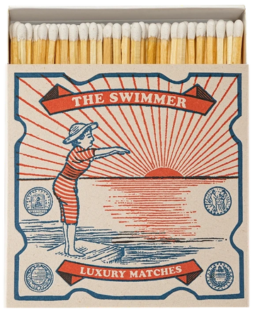 Caja de cerillas cuadrada con ilustración vintage de una mujer con bañador de rayas rojas y blancas saltando al mar, con cerillas largas de madera y punta blanca.