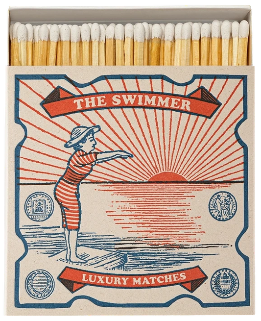 Caja de cerillas cuadrada con ilustración vintage de una mujer con bañador de rayas rojas y blancas saltando al mar, con cerillas largas de madera y punta blanca.