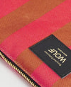 Bolso de mano tipo sobre de gran tamaño con estampado de rayas en tonos naranja y rosa, con cierre de cremallera superior y etiqueta de cuero
