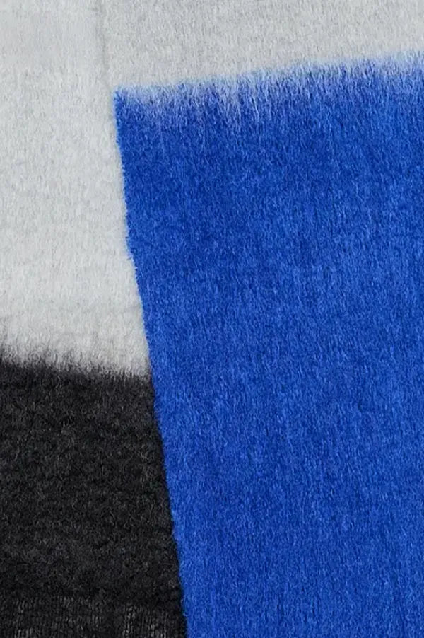 Bufanda de mohair con diseño de bloques de color en tonos contrastados, textura voluminosa de pelo suave y flecos largos hechos a mano en los extremos.