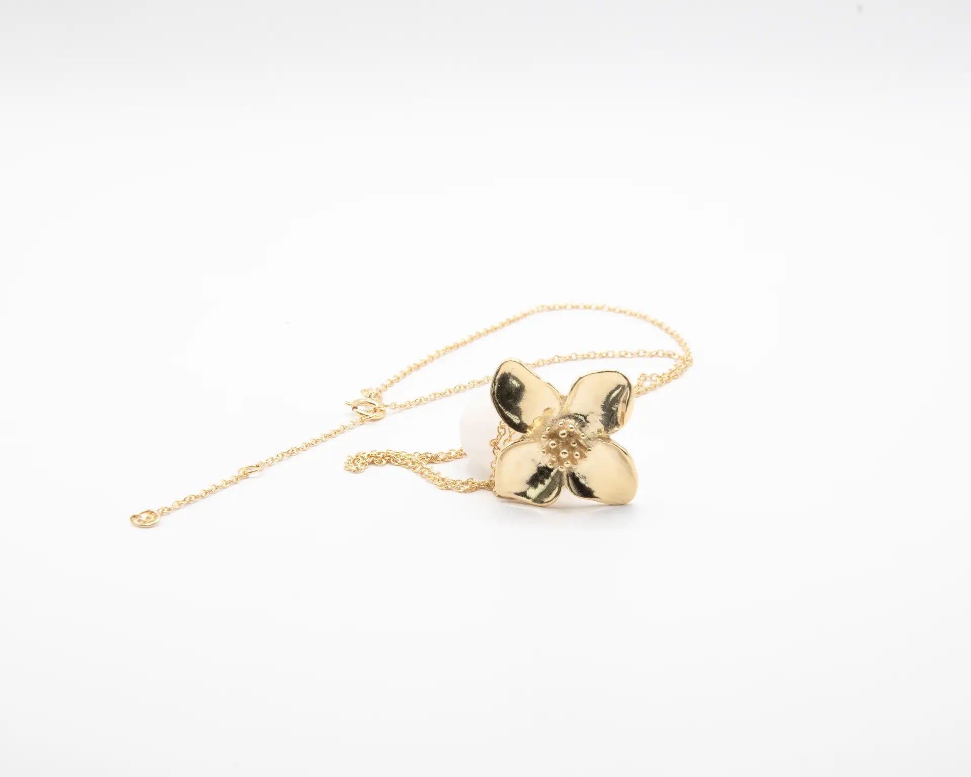 Colgante minimalista con flor de cuatro pétalos en acabado dorado sobre plata de ley 925, cadena fina, joyería artesanal Pipa Pirita colección De la Tierra