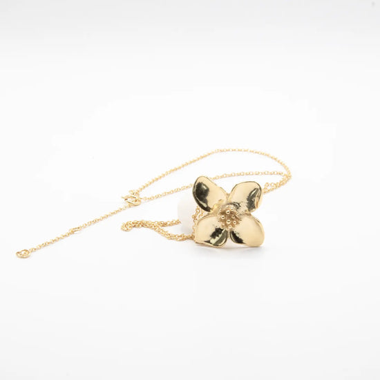 Colgante minimalista con flor de cuatro pétalos en acabado dorado sobre plata de ley 925, cadena fina, joyería artesanal Pipa Pirita colección De la Tierra