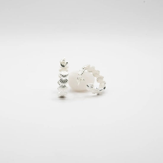 Pendientes de aro en plata de ley con detalle de conchas marinas esculpidas, cierre de presión y acabado artesanal de la marca de joyas Pipa Pirita.