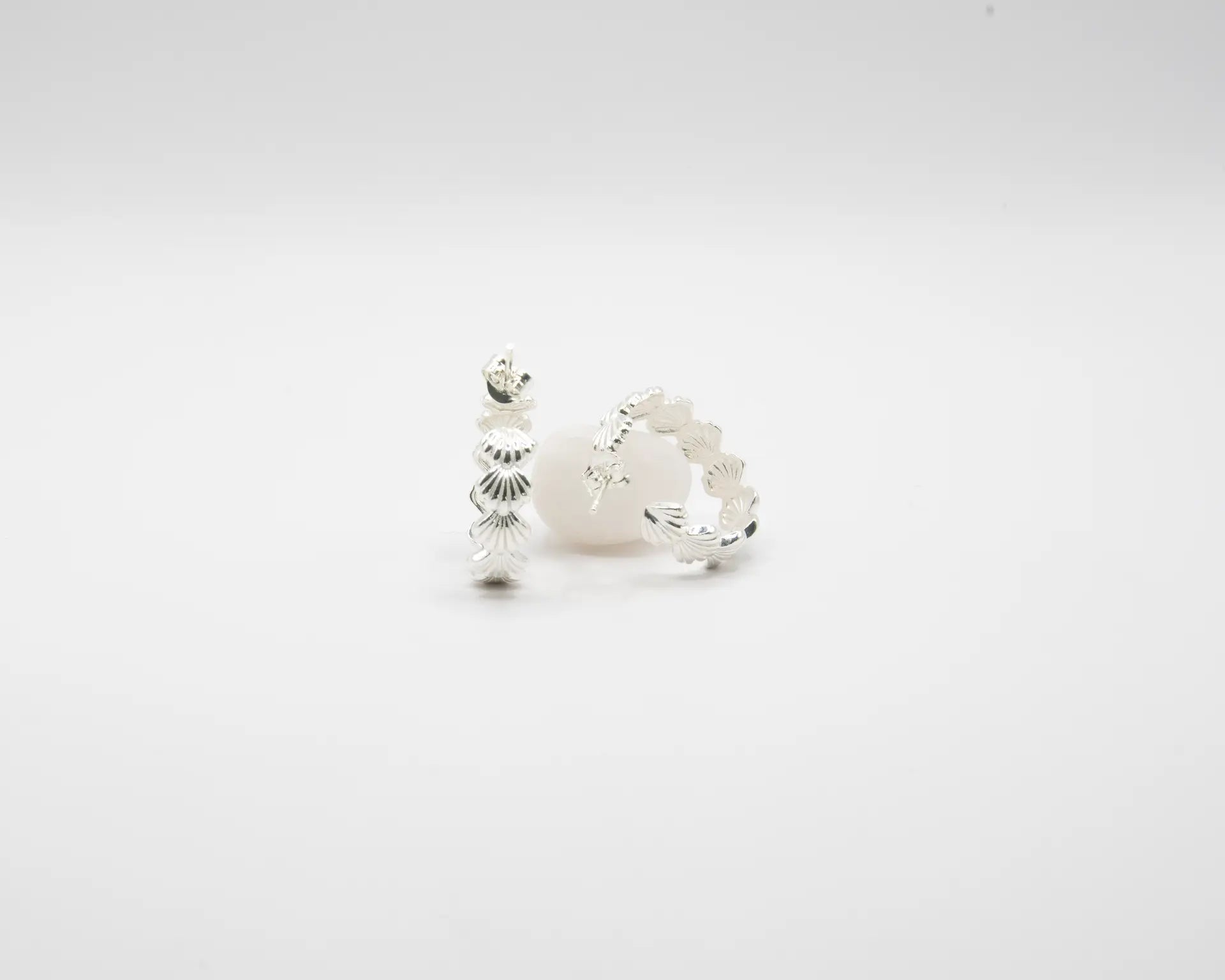 Pendientes de aro en plata de ley con detalle de conchas marinas esculpidas, cierre de presión y acabado artesanal de la marca de joyas Pipa Pirita.