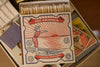 Caja de cerillas cuadrada con ilustración vintage de una mujer con bañador de rayas rojas y blancas saltando al mar, con cerillas largas de madera y punta blanca.