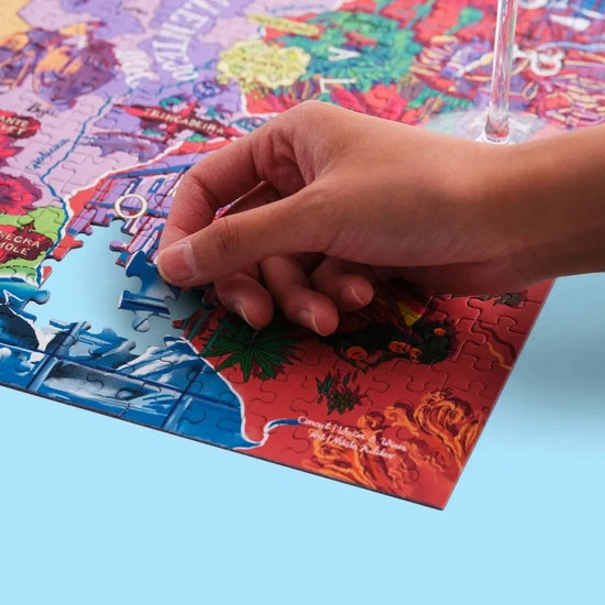 Puzzle de 1000 piezas que representa un mapa ilustrado de Portugal con sus regiones vinícolas, variedades de uva y elementos culturales sobre un fondo azul oscuro.