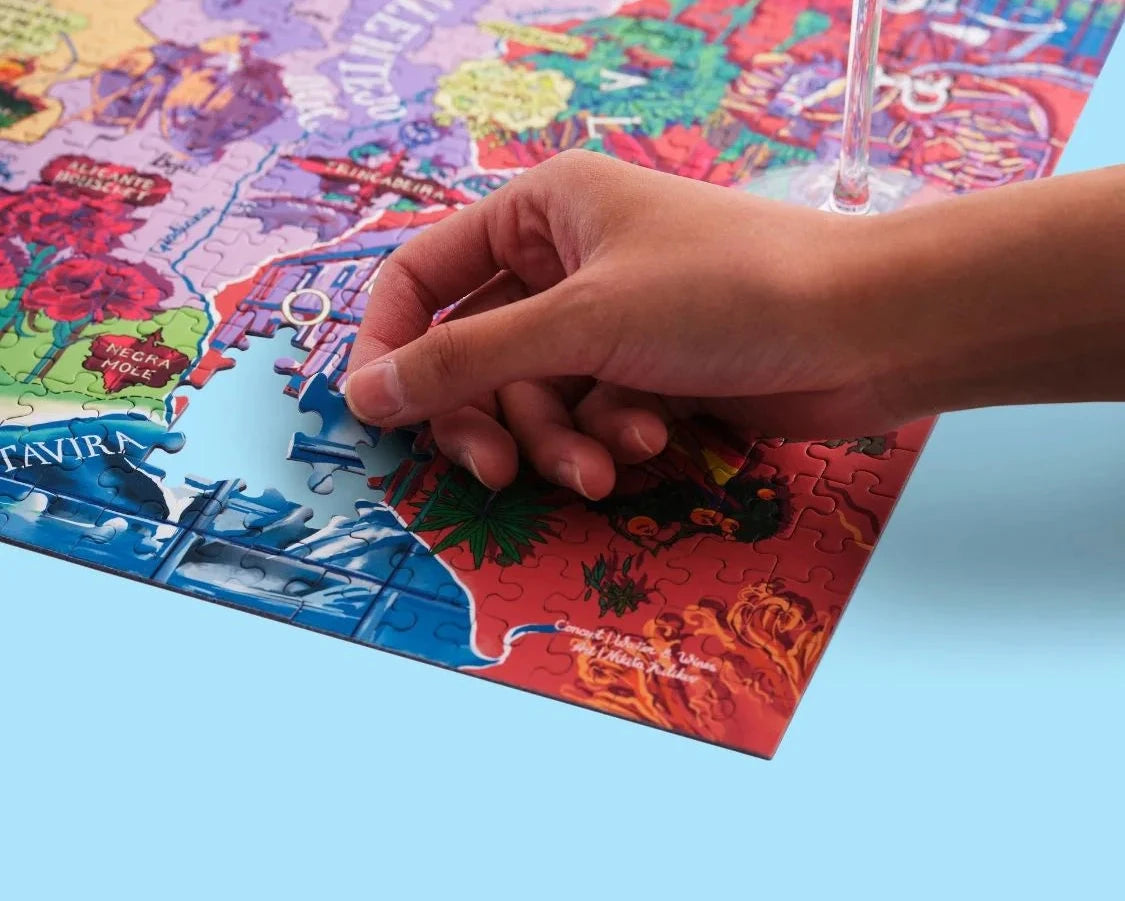 Puzzle de 1000 piezas que representa un mapa ilustrado de Portugal con sus regiones vinícolas, variedades de uva y elementos culturales sobre un fondo azul oscuro.