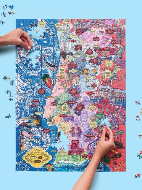 Puzzle de 1000 piezas que representa un mapa ilustrado de Portugal con sus regiones vinícolas, variedades de uva y elementos culturales sobre un fondo azul oscuro.