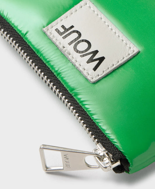 Cartera pequeña de color verde oscuro con acabado brillante, cierre de cremallera superior, ranura trasera de cuero para tarjetas y etiqueta frontal de Wouf