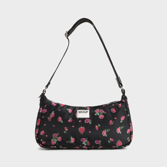 Bolso de hombro con estampado floral colorido sobre fondo oscuro, silueta suave y relajada, con correa ajustable negra y etiqueta de cuero reciclado de Wouf.