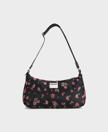 Bolso de hombro con estampado floral colorido sobre fondo oscuro, silueta suave y relajada, con correa ajustable negra y etiqueta de cuero reciclado de Wouf.