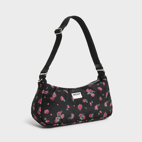 Bolso de hombro con estampado floral colorido sobre fondo oscuro, silueta suave y relajada, con correa ajustable negra y etiqueta de cuero reciclado de Wouf.