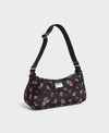 Bolso de hombro con estampado floral colorido sobre fondo oscuro, silueta suave y relajada, con correa ajustable negra y etiqueta de cuero reciclado de Wouf.