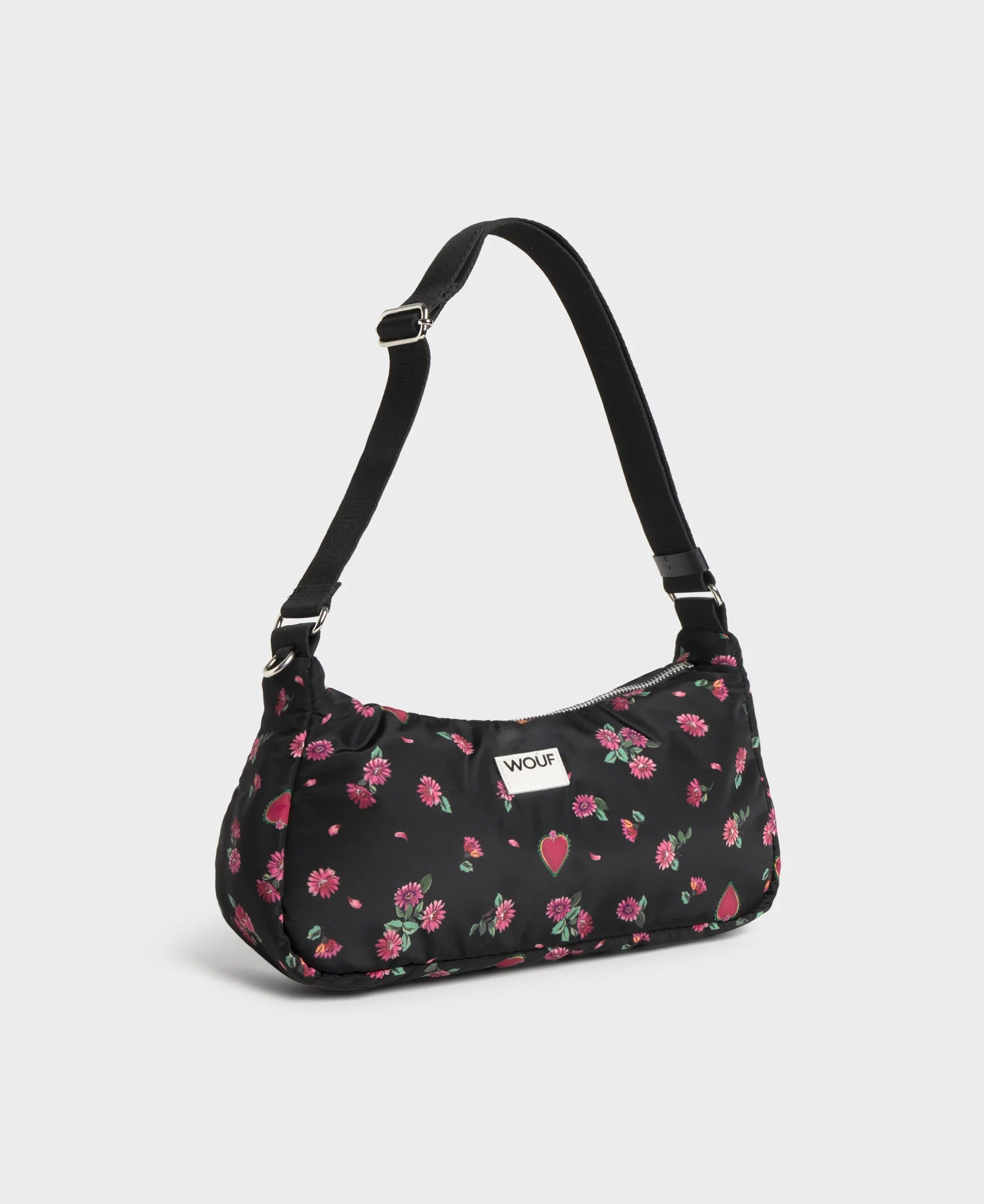 Bolso de hombro con estampado floral colorido sobre fondo oscuro, silueta suave y relajada, con correa ajustable negra y etiqueta de cuero reciclado de Wouf.
