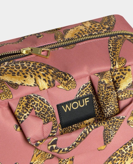 Neceser de gran tamaño con estampado de leopardo en tonos negros y marrones sobre fondo rosa claro, con cierre de cremallera superior y etiqueta de cuero de Wouf.
