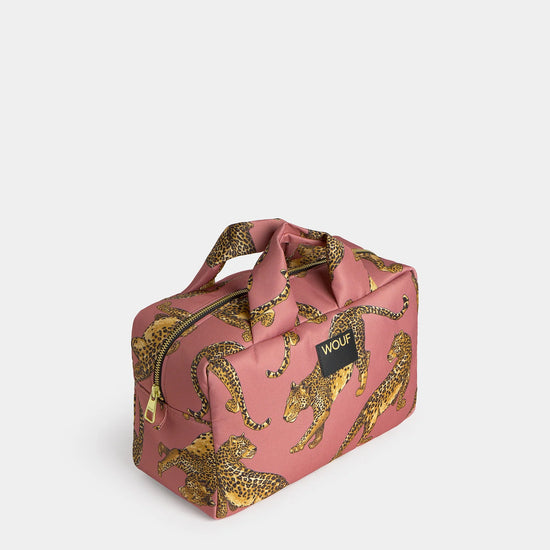 Neceser de gran tamaño con estampado de leopardo en tonos negros y marrones sobre fondo rosa claro, con cierre de cremallera superior y etiqueta de cuero de Wouf.