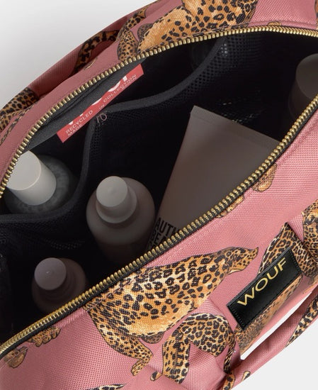 Neceser de gran tamaño con estampado de leopardo en tonos negros y marrones sobre fondo rosa claro, con cierre de cremallera superior y etiqueta de cuero de Wouf.