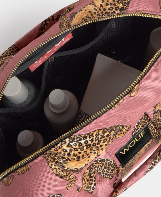 Neceser de gran tamaño con estampado de leopardo en tonos negros y marrones sobre fondo rosa claro, con cierre de cremallera superior y etiqueta de cuero de Wouf.