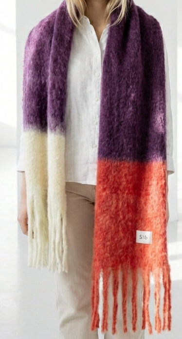 Bufanda de mohair voluminosa con diseño bicolor en morado y rojo, terminada en flecos y con textura de pelo suave, fabricada artesanalmente en Ezcaray.