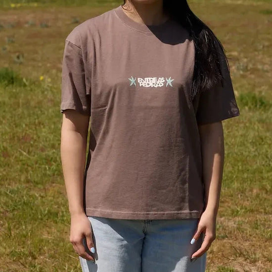 Camiseta de manga corta de corte holgado en color marrón con diseño gráfico "Entre as Pedras", confeccionada en algodón orgánico de la marca NWHR.