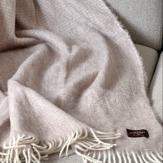 Manta de sofá de mohair en color beige crema con textura voluminosa de pelo suave, terminada con flecos y fabricada de forma artesanal en Ezcaray.