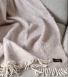 Manta de sofá de mohair en color beige crema con textura voluminosa de pelo suave, terminada con flecos y fabricada de forma artesanal en Ezcaray.