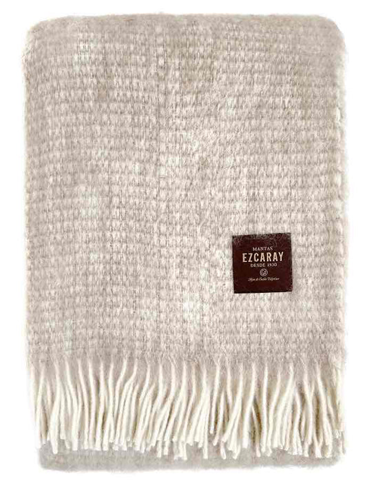 Manta de sofá de mohair en color beige crema con textura voluminosa de pelo suave, terminada con flecos y fabricada de forma artesanal en Ezcaray.