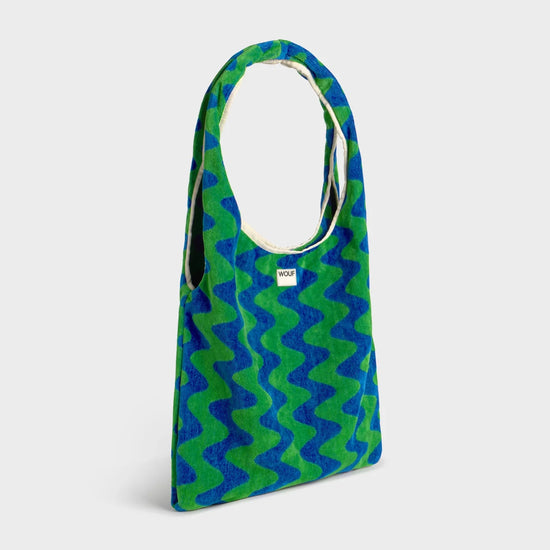 Bolso grande tipo camiseta en tejido de rizo de algodón orgánico color crudo, de tacto toalla con asas integradas y etiqueta de silicona, marca Wouf.