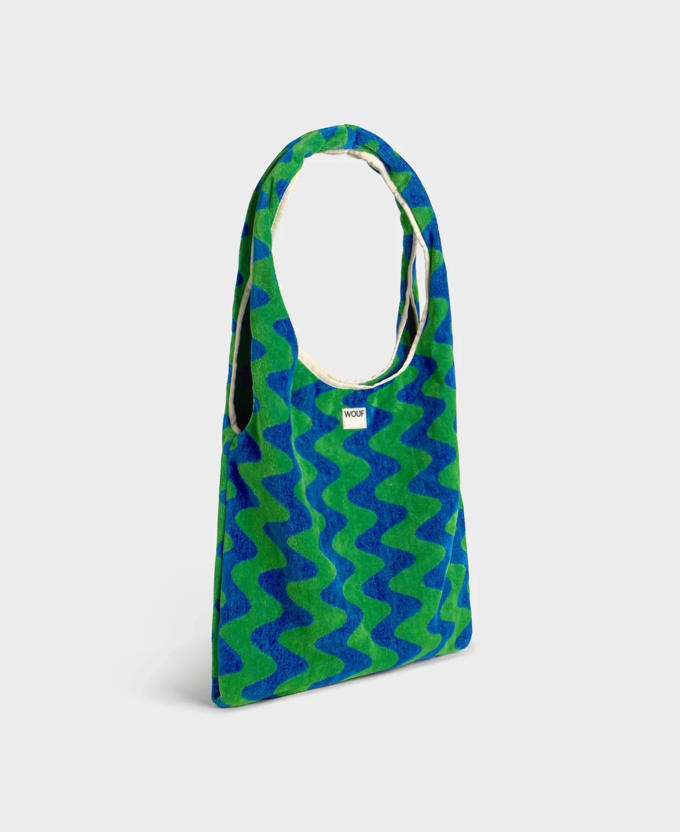 Bolso grande tipo camiseta en tejido de rizo de algodón orgánico color crudo, de tacto toalla con asas integradas y etiqueta de silicona, marca Wouf.