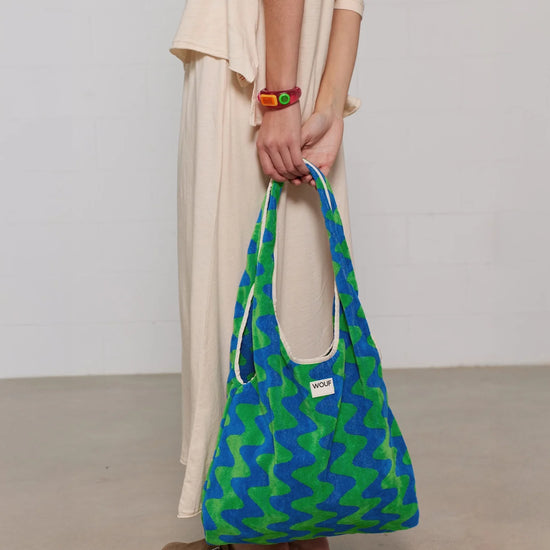 Bolso grande tipo camiseta en tejido de rizo de algodón orgánico color crudo, de tacto toalla con asas integradas y etiqueta de silicona, marca Wouf.