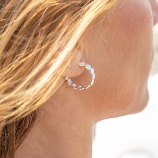Pendientes de aro en plata de ley con detalle de conchas marinas esculpidas, cierre de presión y acabado artesanal de la marca de joyas Pipa Pirita.