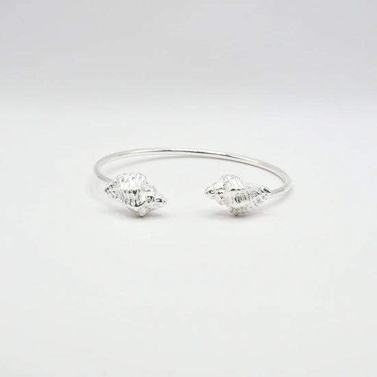 

Pulsera torque abierta con caracolas en los extremos, acabado plata, colección Del Mar de Pipa Pirita, joyería artesanal de inspiración atlántica