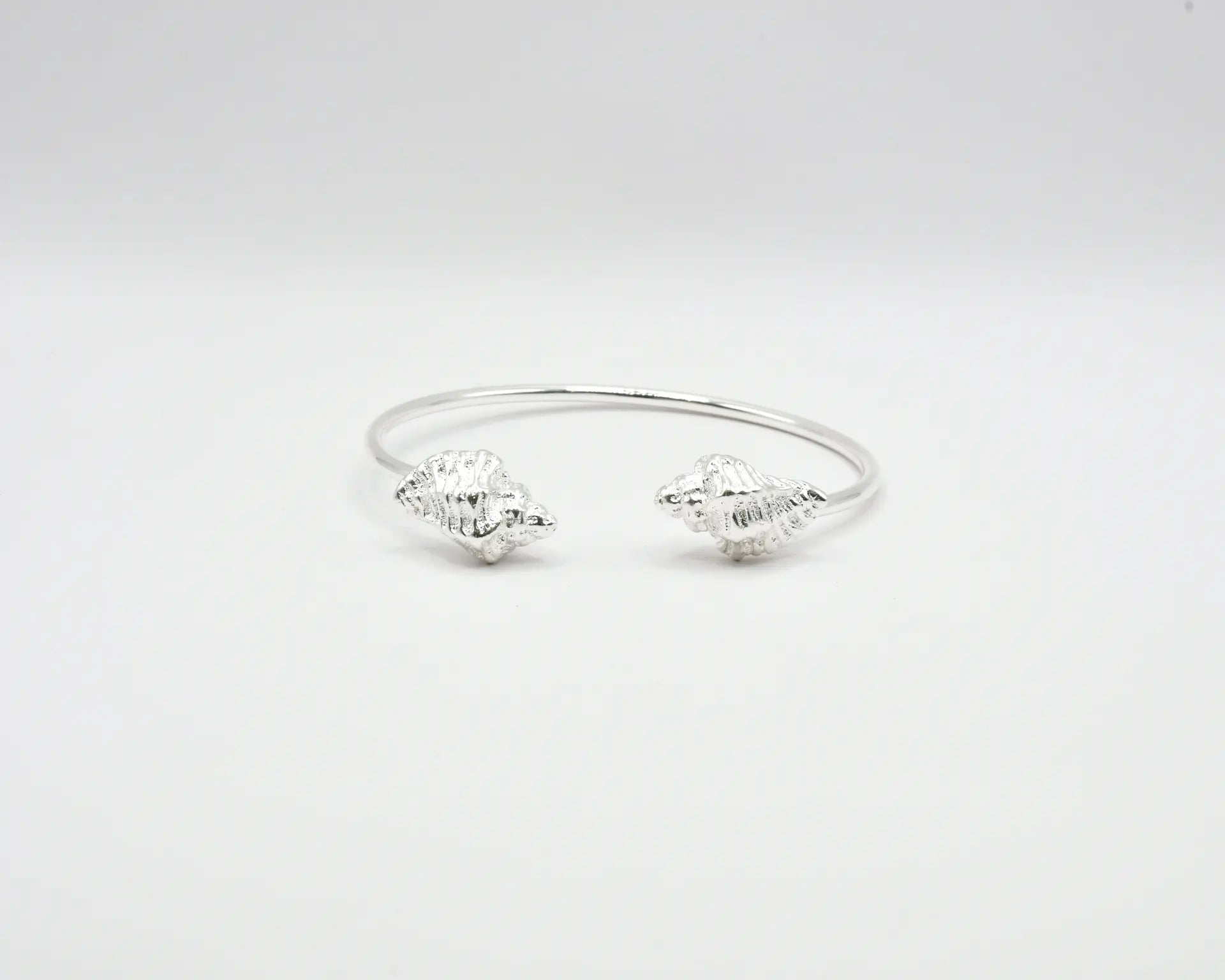 

Pulsera torque abierta con caracolas en los extremos, acabado plata, colección Del Mar de Pipa Pirita, joyería artesanal de inspiración atlántica