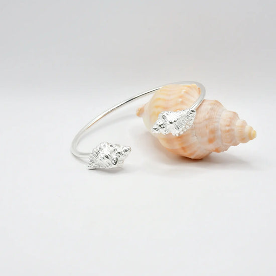 

Pulsera torque abierta con caracolas en los extremos, acabado plata, colección Del Mar de Pipa Pirita, joyería artesanal de inspiración atlántica