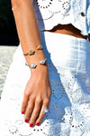 

Pulsera torque abierta con caracolas en los extremos, acabado plata, colección Del Mar de Pipa Pirita, joyería artesanal de inspiración atlántica