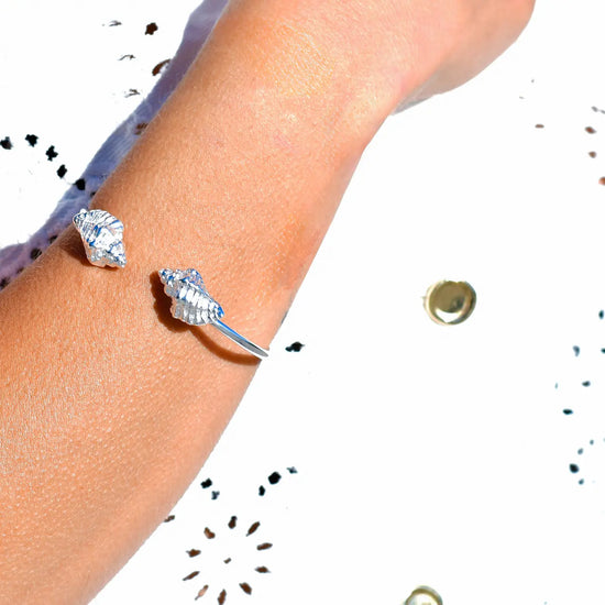 

Pulsera torque abierta con caracolas en los extremos, acabado plata, colección Del Mar de Pipa Pirita, joyería artesanal de inspiración atlántica