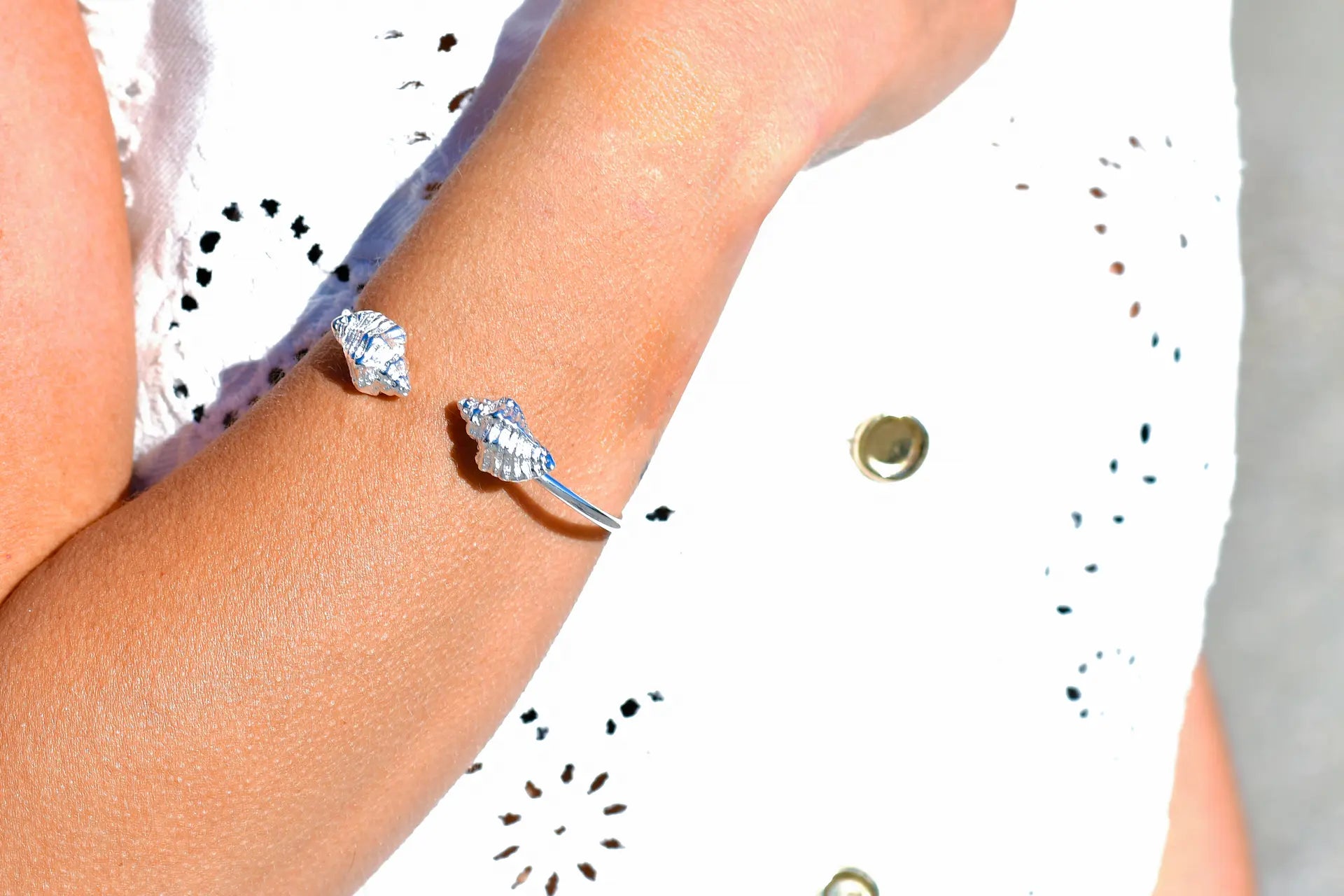 

Pulsera torque abierta con caracolas en los extremos, acabado plata, colección Del Mar de Pipa Pirita, joyería artesanal de inspiración atlántica
