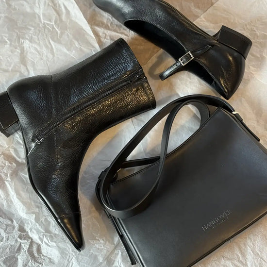 Bolso pequeño estructurado de piel napa negra con asa ajustable y diseño minimalista de la marca Hangover of Fashion, fabricado artesanalmente en España.