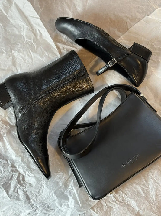 Bolso pequeño estructurado de piel napa negra con asa ajustable y diseño minimalista de la marca Hangover of Fashion, fabricado artesanalmente en España.