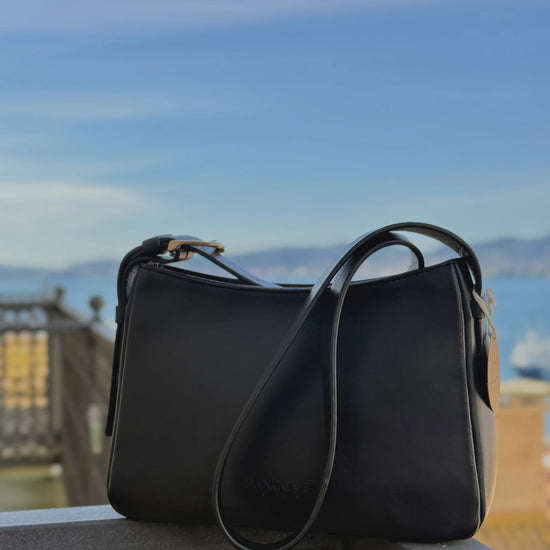 Bolso pequeño estructurado de piel napa negra con asa ajustable y diseño minimalista de la marca Hangover of Fashion, fabricado artesanalmente en España.