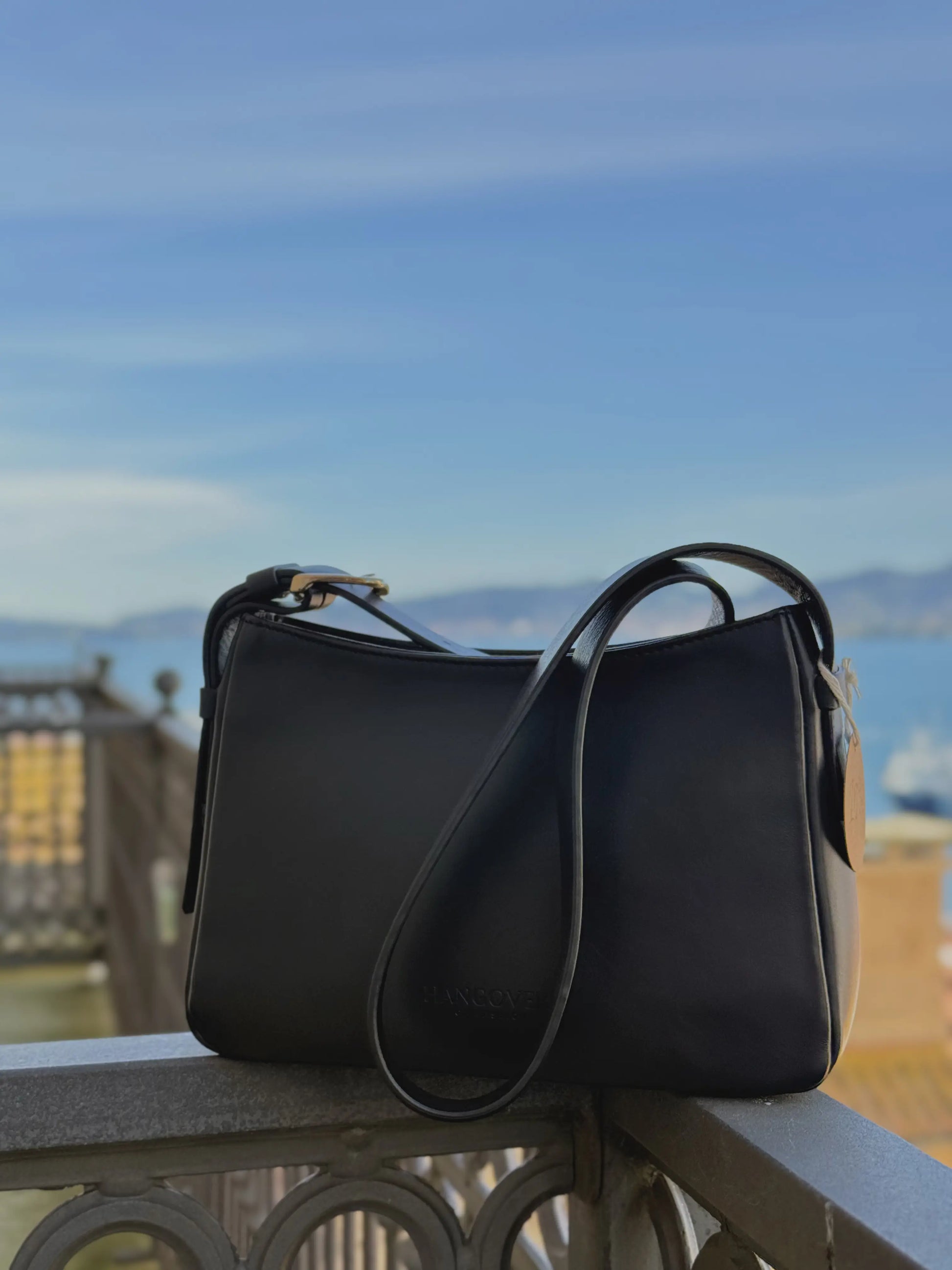 Bolso pequeño estructurado de piel napa negra con asa ajustable y diseño minimalista de la marca Hangover of Fashion, fabricado artesanalmente en España.
