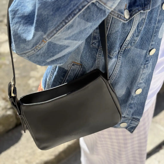 Bolso pequeño estructurado de piel napa negra con asa ajustable y diseño minimalista de la marca Hangover of Fashion, fabricado artesanalmente en España.