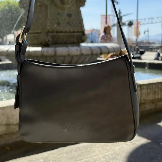 Bolso pequeño estructurado de piel napa negra con asa ajustable y diseño minimalista de la marca Hangover of Fashion, fabricado artesanalmente en España.