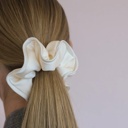 Coletero tipo scrunchie gigante de color blanco roto con capas de tela en forma de pétalos de flor anémona de la marca danesa By Stær.