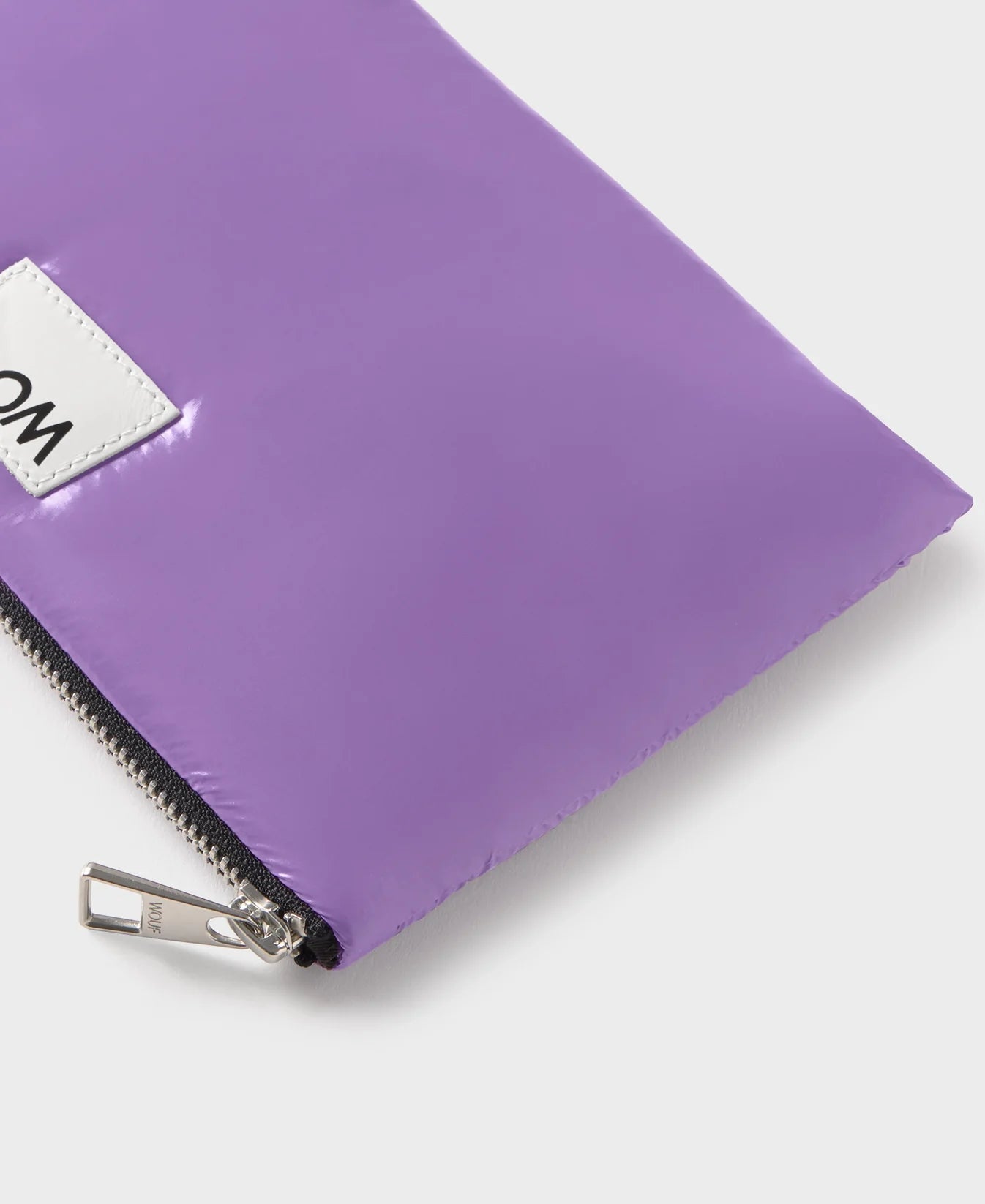 Pequeña funda plana con estampado color  lavanda, acabado brillante, cierre de cremallera superior y etiqueta de piel, modelo Lavender Pouch de Wouf.